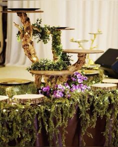 a table topped with lots of cakes covered in greenery