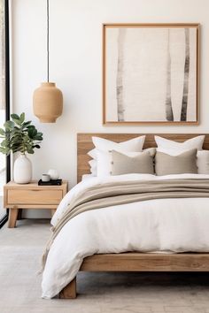 a bed with white sheets and pillows in a bedroom next to a painting on the wall