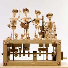 a group of wooden skeleton figurines sitting on top of a musical instrument in front of a white background