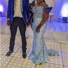 a man and woman standing next to each other on a dance floor with lights all around them