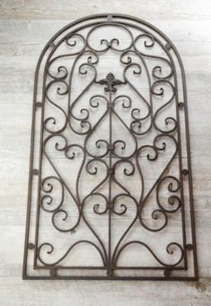 an ornate iron window on the side of a building with white paint and wood flooring