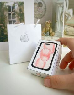 a hand is holding an apple phone in front of a box with the iphone logo on it