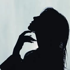 the silhouette of a woman holding her hand up to her mouth