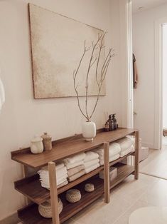 a wooden shelf with towels on it next to a painting and toilet in a bathroom