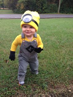 a little boy in a minion costume standing on the grass with his eyes closed