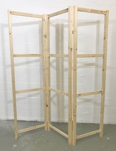 a tall wooden room divider with shelves on the sides and one section open to show it's contents