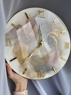 a person holding a marble clock with gold numbers and numerals on the face