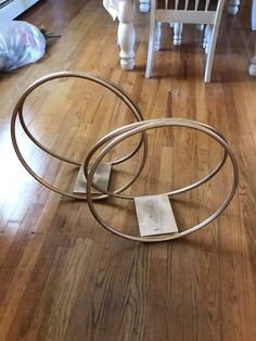 two metal circles sitting on top of a hard wood floor next to a white chair