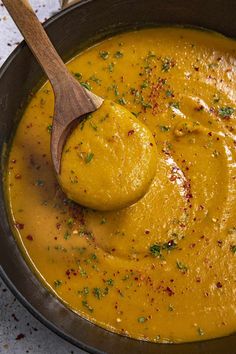 a wooden spoon in a bowl filled with yellow soup