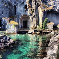 the water is crystal clear and blue in this cave like area with stairs leading up to it's entrance