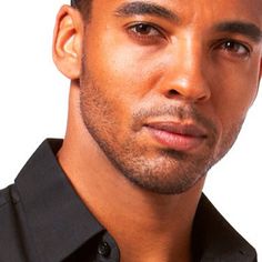 a close up of a person wearing a black shirt and looking at the camera with a serious look on his face