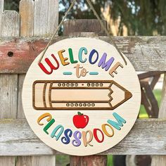 a welcome sign hanging on the side of a wooden fence with an apple and pencil