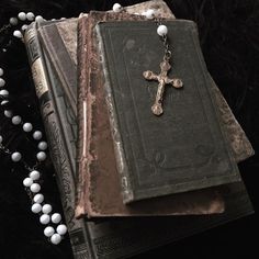 an old book with a cross on it next to a beaded necklace and rosary