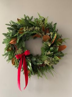 a green wreath with red ribbon hanging on the wall