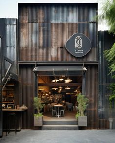 the outside of a restaurant with stairs leading up to it's entrance and potted plants on either side