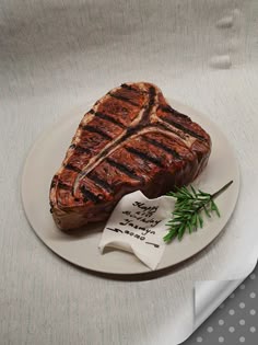 a piece of steak sitting on top of a white plate next to a fork and napkin