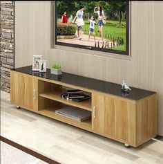 an entertainment center with a television on the wall and people running in the park behind it