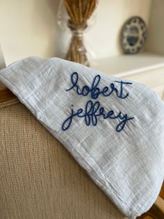 an embroidered pillow on top of a chair with the word robert jeffy written on it