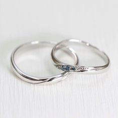 two wedding rings with blue and white diamonds