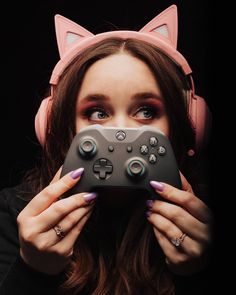 a woman with headphones on holding a video game controller in front of her face