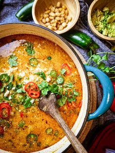 a large pot filled with food next to bowls of beans and other foods on a table