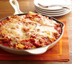 a casserole dish with meat and cheese in it sitting on a place mat