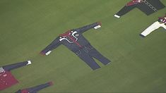 an aerial view of three men in suits and ties on a green grass covered field