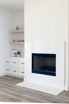 an empty room with a white fireplace and shelves