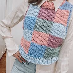 a woman wearing a multicolored knitted vest and tie with her hands on her hips