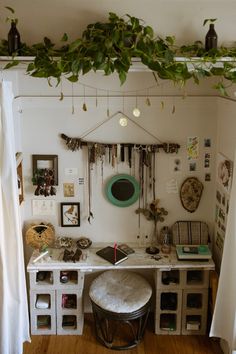 a white desk topped with lots of drawers under a green leafy plant hanging from the ceiling