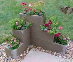 four cement planters with flowers growing out of them