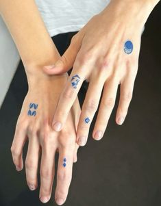 two hands with blue and white designs on their fingers, one holding the other's hand