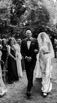 a bride and groom walking down the aisle at their wedding ceremony in black and white