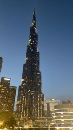 the burj building is lit up at night in front of other tall buildings