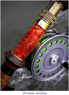 a fishing rod with a reel attached to it and some water in the back ground