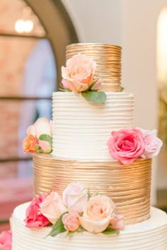 a three tiered wedding cake with pink and orange flowers on it's side