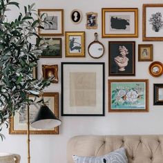 a living room filled with lots of framed pictures on the wall next to a couch