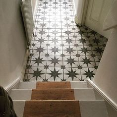 an open door leading to a white and black tiled floor with stairs in the hallway