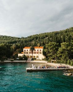 a large house sitting on top of a lush green hillside next to a body of water