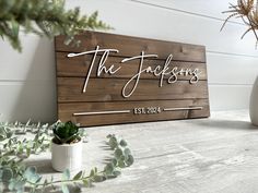 a wooden sign that says the jacksons on it next to some potted plants