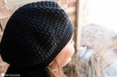 a woman wearing a black knitted hat looking out the window