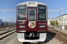 the train is stopped on the tracks near many buildings and power lines in the background