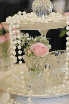 a vase filled with flowers sitting on top of a white table covered in glass beads