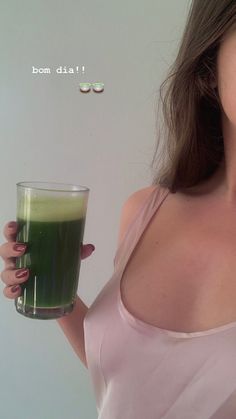 a woman holding a glass with green liquid in it