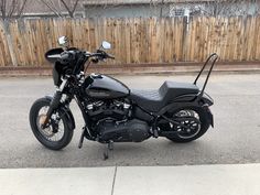 a black motorcycle parked in front of a wooden fence