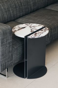 a black and white marble coffee table next to a gray couch with a grey sofa in the background