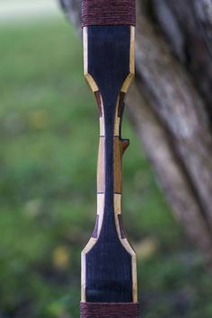 the back end of a wooden bird feeder hanging from a tree branch with grass in the background