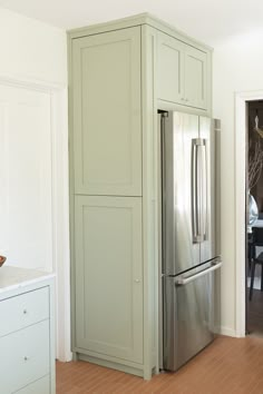 a large stainless steel refrigerator in a kitchen with wood flooring and white painted walls