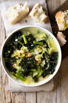 a white bowl filled with vegetables next to bread