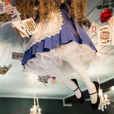 a doll hanging from the ceiling in a room with cards on it's legs